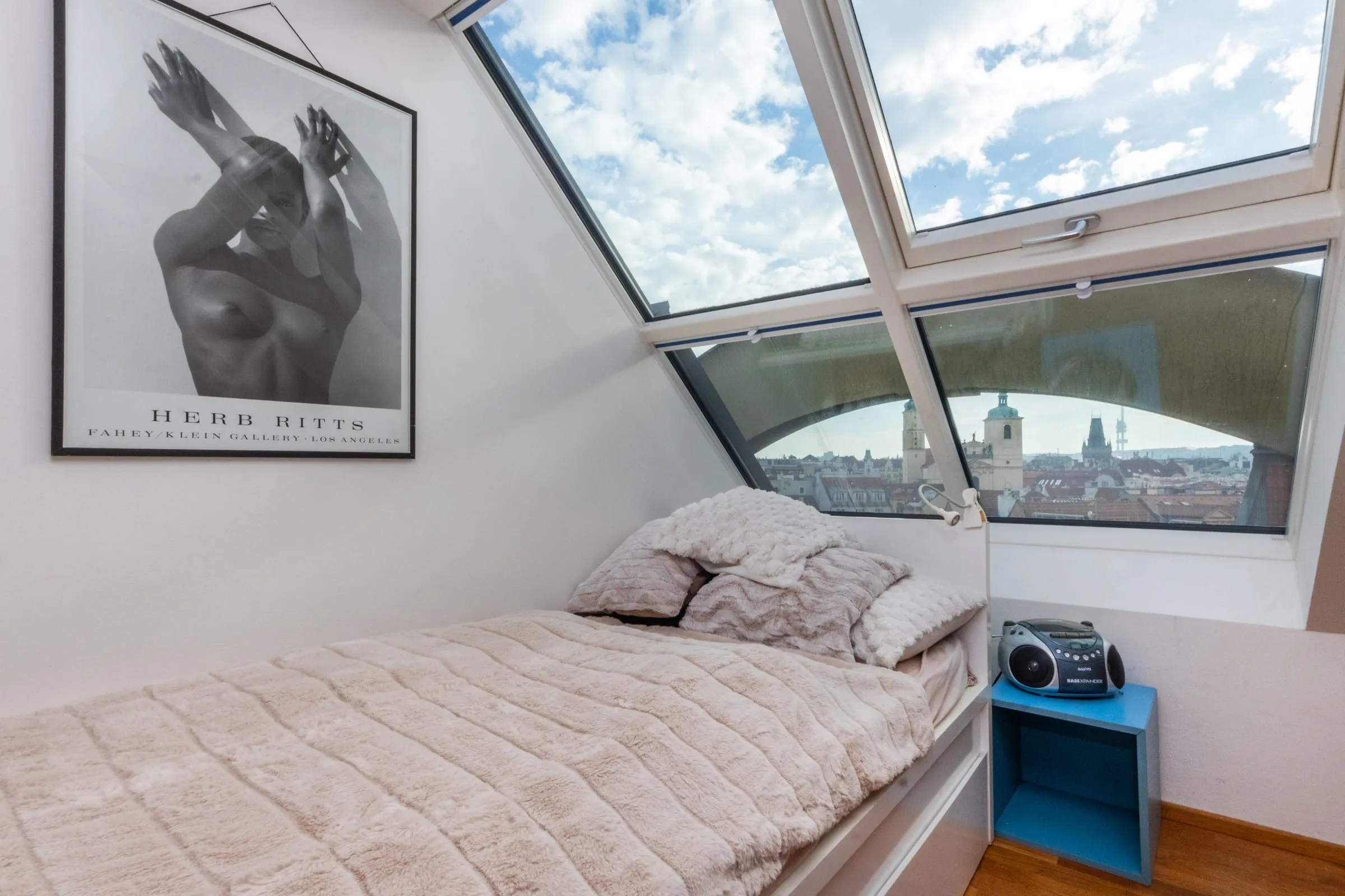 Bed under a large studio window with a view over the Old Town rooftops