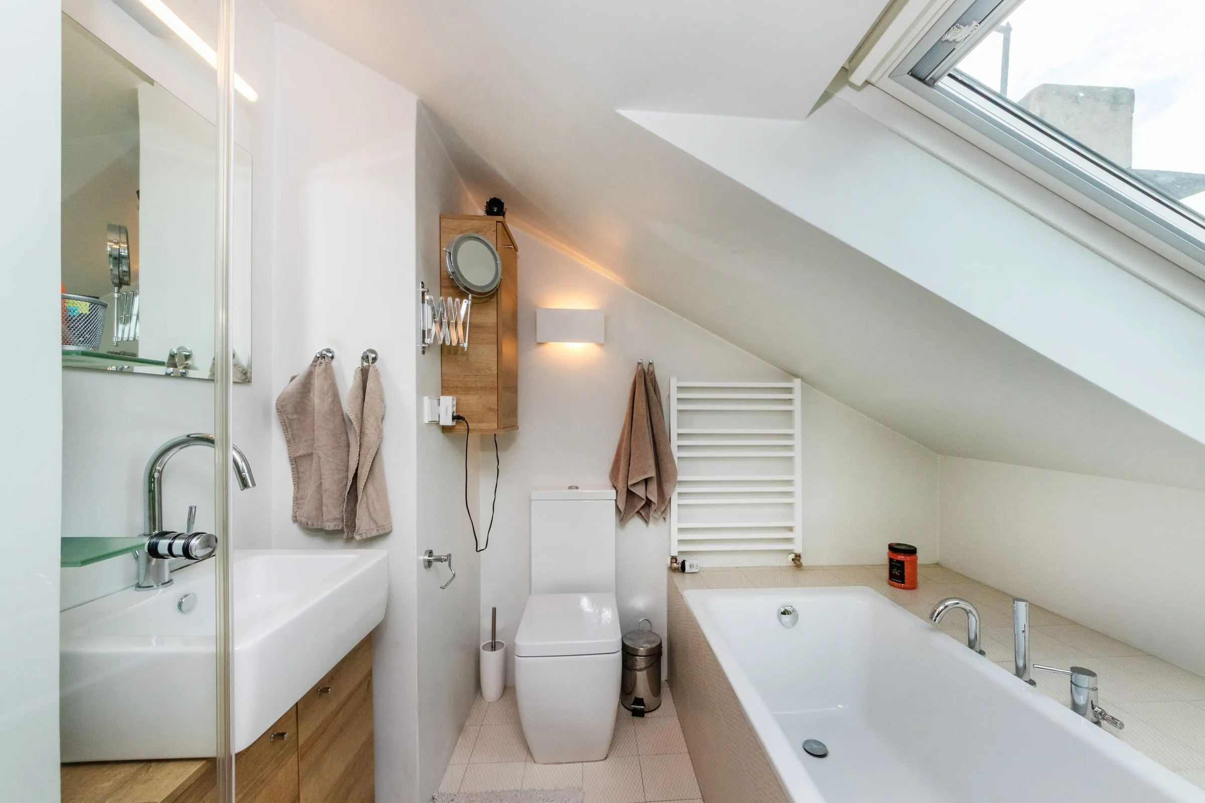 Upstairs bathroom with a sink and a tub under the sloping ceiling, looking out to Prague Castle