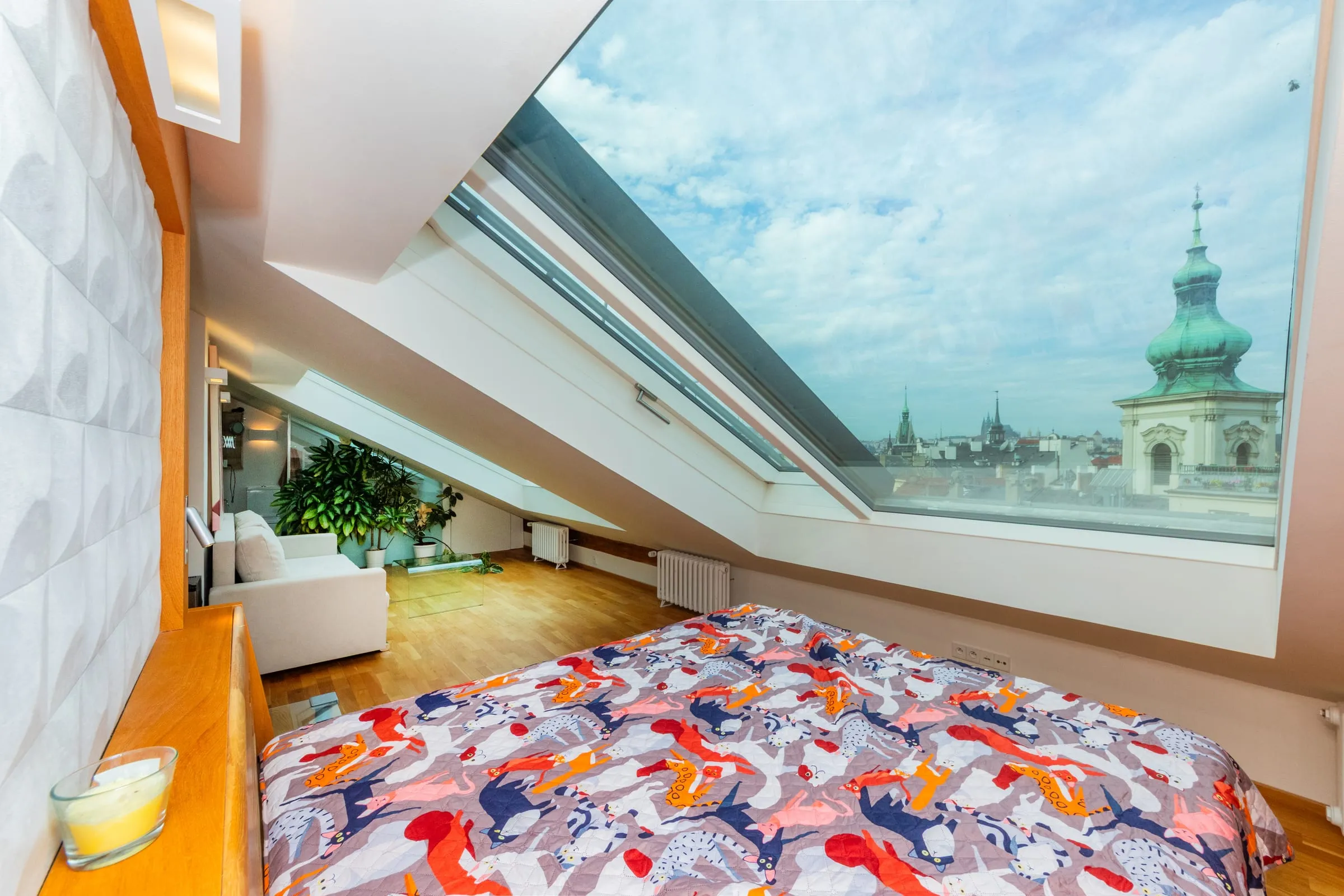 Bed under skylights that frame the Týn Church towers